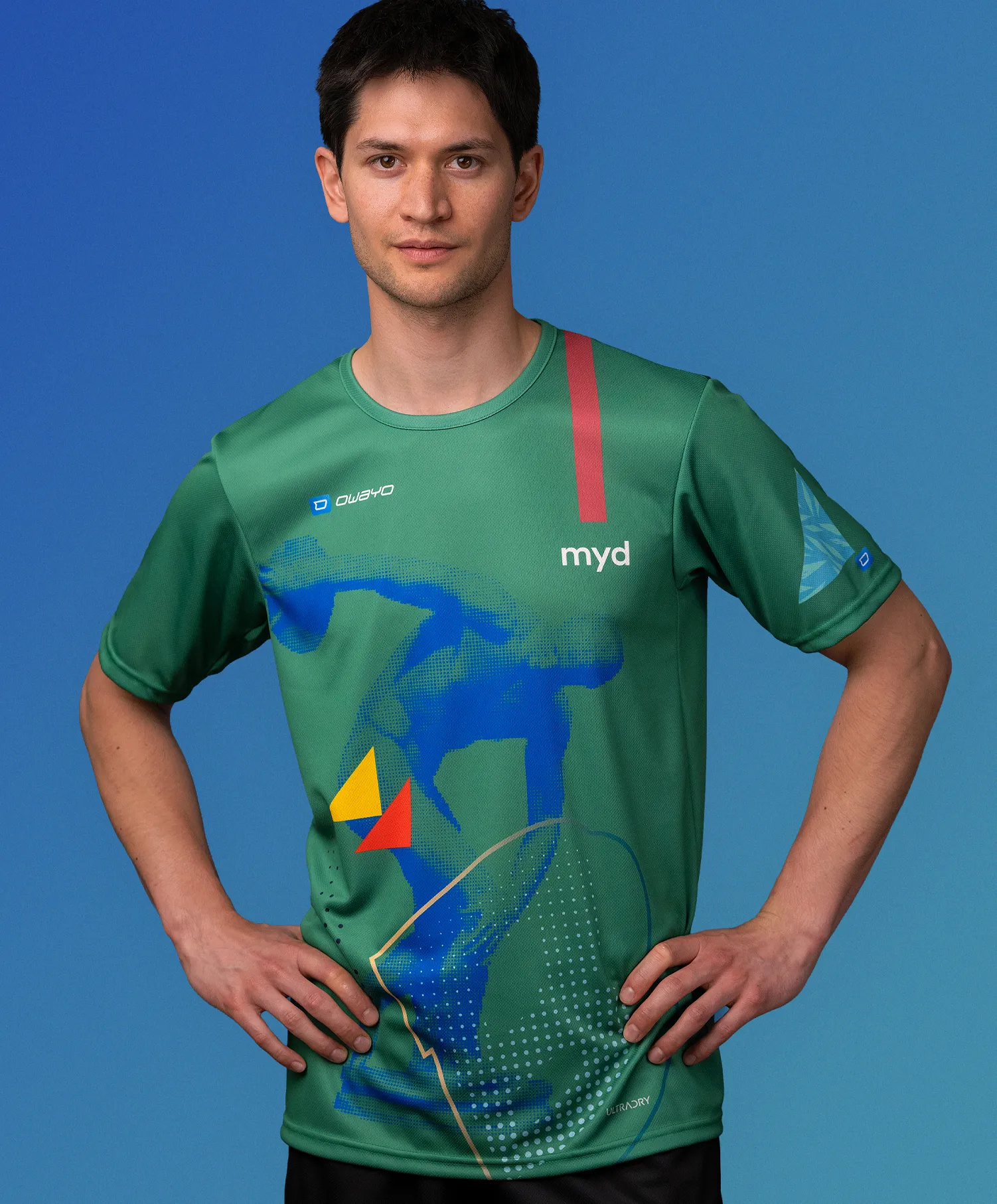 Ein Mann in einem grünen, maßgeschneiderten Sporttrikot von owayo mit einem blauen, gelben und roten grafischen Design und der Aufschrift 'myd' auf der Brust.