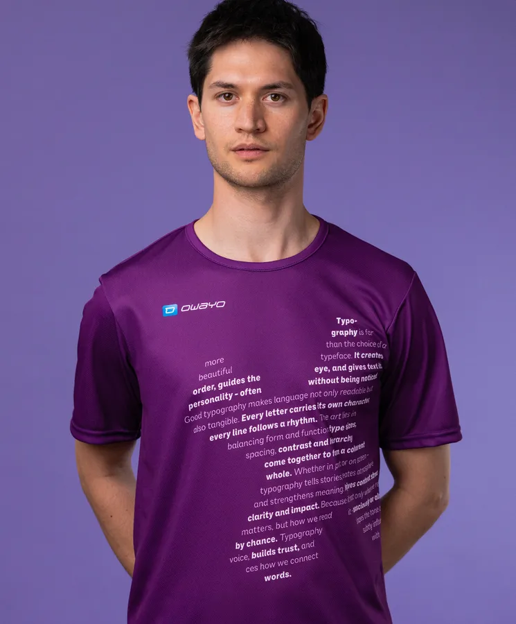 Ein Mann trägt ein lila Sportshirt mit typografischen Texten auf der Vorderseite, vor einem lila Hintergrund.