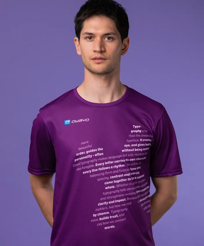 Ein Mann trägt ein lila Sportshirt mit typografischen Texten auf der Vorderseite, vor einem lila Hintergrund.