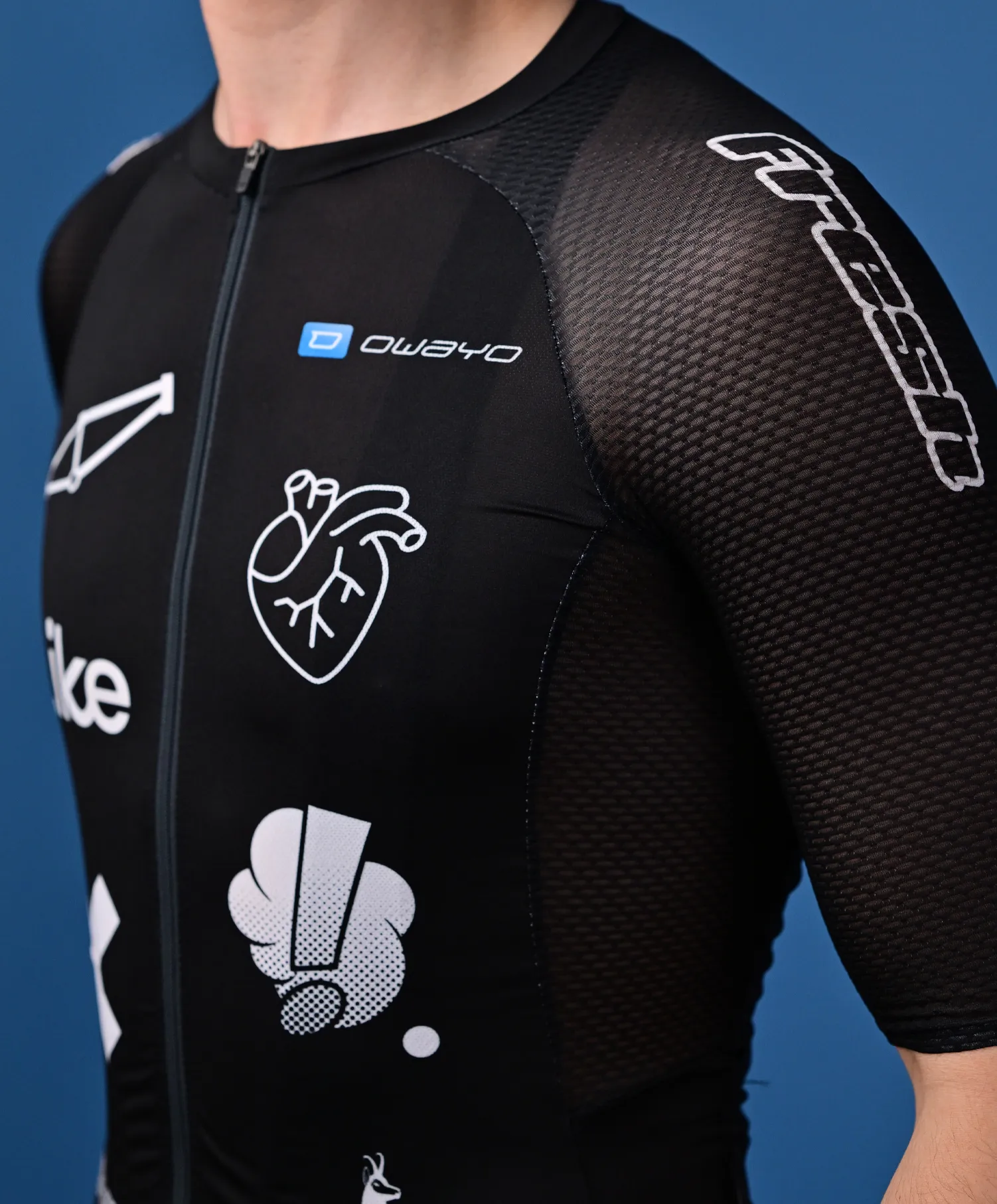 Eine Person trägt ein schwarzes, ärmelloses Sporttrikot von owayo mit einem Reißverschluss vorne, das verschiedene weiße Logos und Grafiken, darunter ein Herz und ein stilisiertes 'O', auf der Brust und dem Ärmel zeigt.