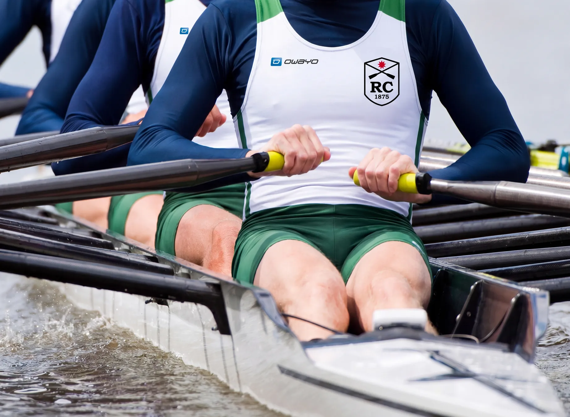 Drei Ruderer in maßgeschneiderter Sportbekleidung rudern synchron in einem Boot.